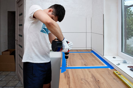 repairman using electric drill and installation new modern kitchenの写真素材