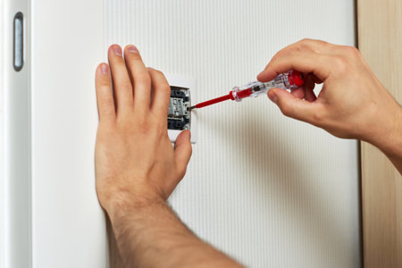 electrician working on light switch using screwdriver inside, close-up