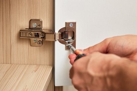 handyman assembling cabinet and screwing door hinge at home, close-upの写真素材