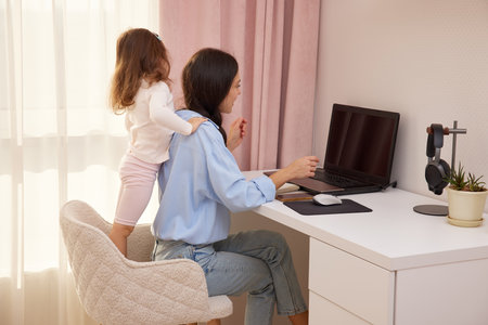 Happy mother hugging daughter during remote work from a home officeの写真素材