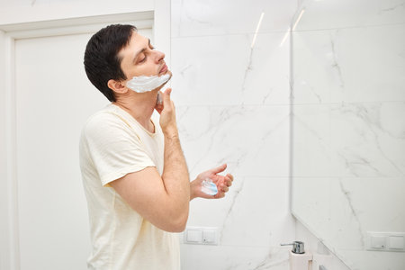 Man applying shaving foam to his face for a morning shave routineの写真素材