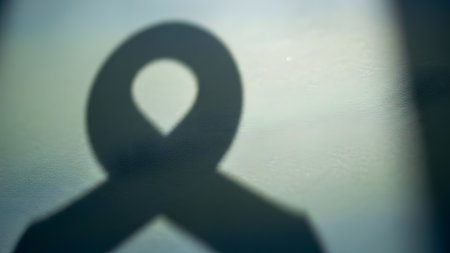 Shadow of awareness ribbon on a plain surface symbolizing support and cause awareness.の素材