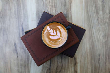 Coffee latte on wooden table and books.