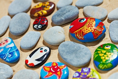 Round colorful stones pebbles shingle with pictures painted on themの写真素材
