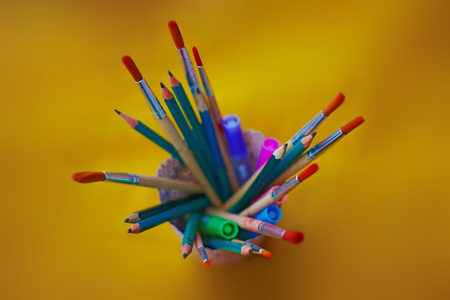 Brushes and pencils in glass on yellow backgroundの写真素材