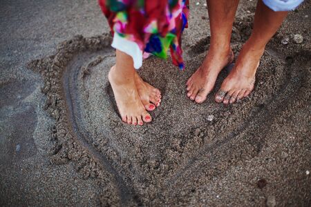 Two lovers on beach drawing heartの写真素材