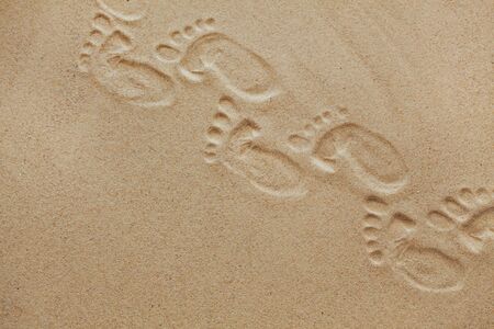 Cute baby footsteps on sandy beach with space for text or desighn