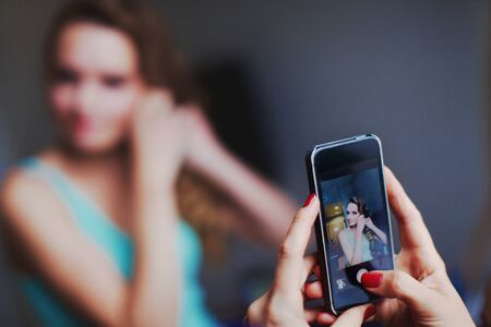 girl is taking her friend picture on smatphone while make upの写真素材