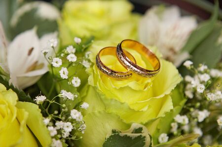 Original wedding rings on beautiful white roses wedding bouquet.の写真素材
