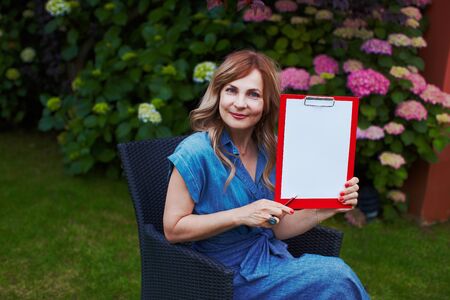 Woman with clipboard at blooming garden working and planning scheduleの写真素材