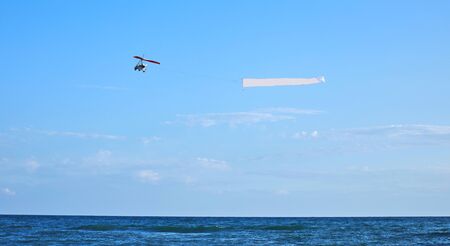 Advertising airplane carryng banner with advertising along crowdy beach