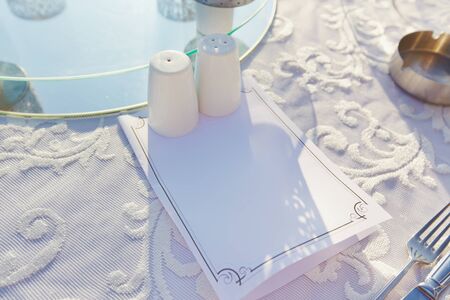 Blank card of menu or evening program on dinning table in restaurant