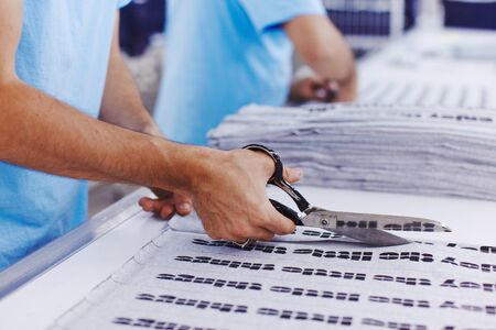 The worker at the factory cuts the fabric with scissors and with cutting machine