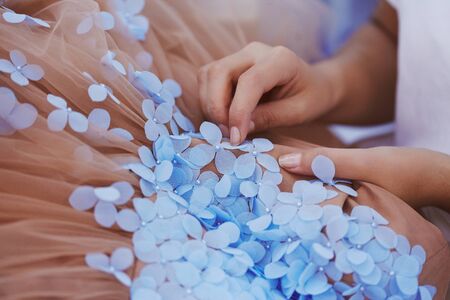 Woman stewing flowers to beautiful nude color dressの写真素材