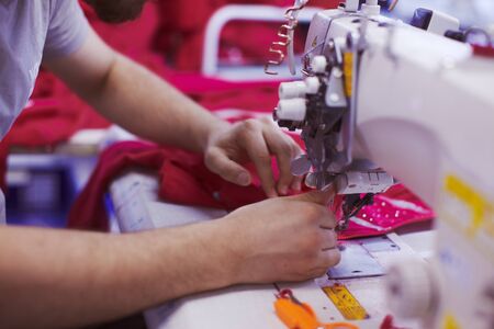 Textile factory workers hands sewing cloth on professional sewing machineの写真素材
