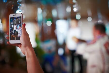 Mother taking picture of her kids on school performance using phone blurredの写真素材