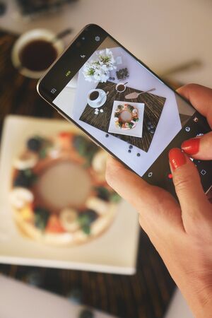 Food blogger taking picture of coffee mousse served with fruits and berriesの写真素材