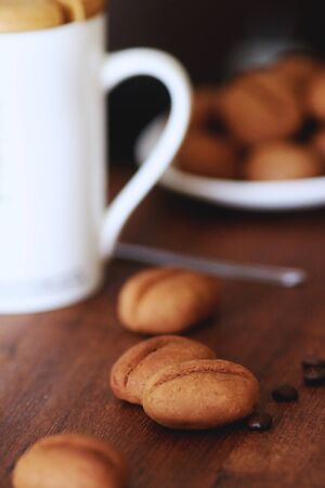 Sweet cookies shaped as cofee beans served with coffee cup