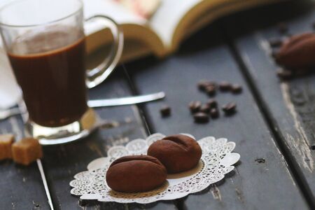 Sweet cookies shaped as cofee beans served with coffee cupの写真素材