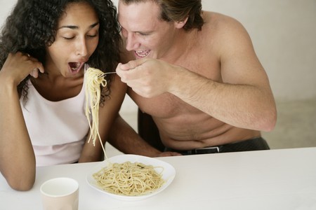 Couple sharing pasta in their kitchenの写真素材