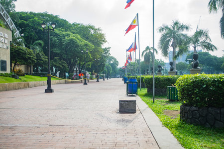 Rizal Park, Manila, Philippines July 2, 2014: A pathway with a row of Philippine flags and trees at the Rizal Park along Taft Ave., Manila, Philippinesのeditorial素材