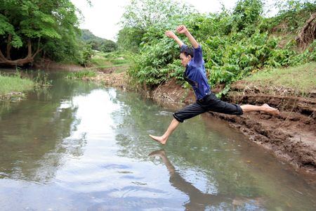 business man jumping on the riverの写真素材