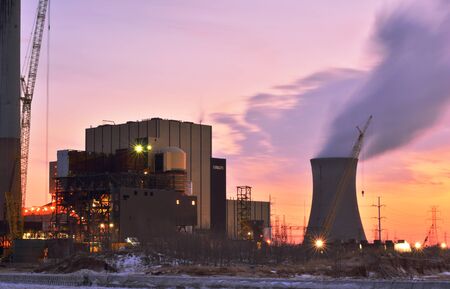 A nuclear power plant is pictured with lights on during a vibrant sunset.のeditorial素材