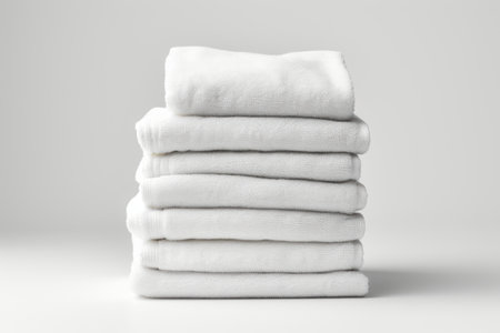 A stack of folded white towels on a table. AI image.の素材