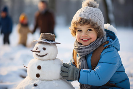 A little boy is building a snowman in the snow. Imaginary AI picture.の素材