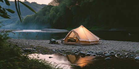 A tent is pitched up on the shore of a river.の素材