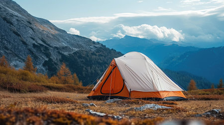 A tent pitched up in a field with mountains in the background.の素材