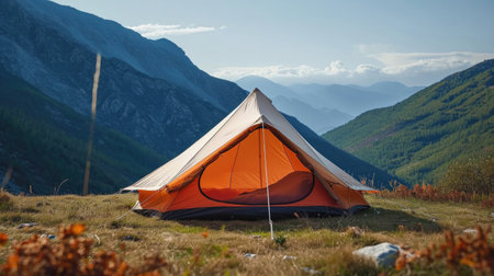 A tent pitched up in a field with mountains in the background.の素材
