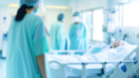 A group of people in scrubs standing around a hospital bed. Blurred defocused blue, white and cyan medical background.の素材