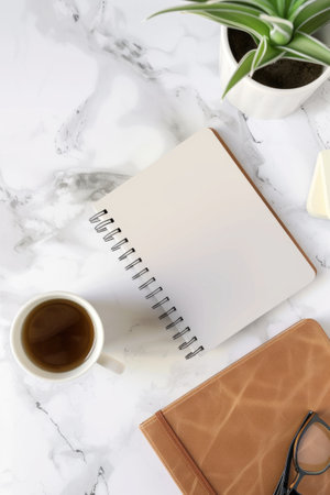 A well-organized desk showcases a vibrant notebook, a sleek pen, stylish eyeglasses, and a lush plant, fostering a creative and productive atmosphere. Blank mockup, copy-space.の素材