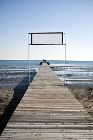 Wooden dock on the beach leading towards the sea, above an empty space to write something intoの写真素材