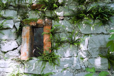 Red window on a stone wall of an abandoned houseの写真素材