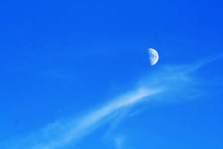 late afternoon blue sky with clouds and moon.の写真素材