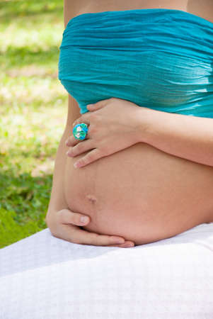 Prengnat woman caressing her huge belly at open airの写真素材