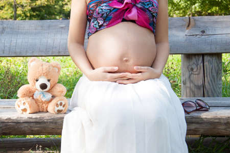 Prengnat woman caressing her huge belly at open air