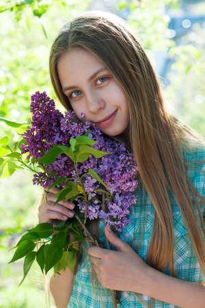 Beautiful girl holding a lilac spring  flowersの写真素材
