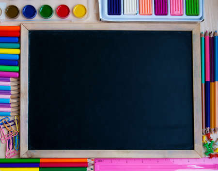 Small elementary blackboard with various paints, crayons and pencils