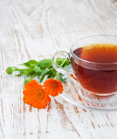 Tea cup with calendula flowers on a wooden backgroundの写真素材