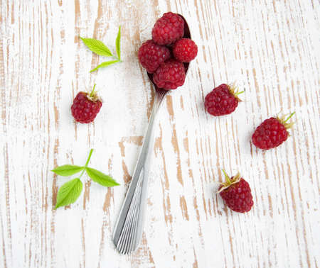 Ripe raspberry on a spoon with green leavesの写真素材