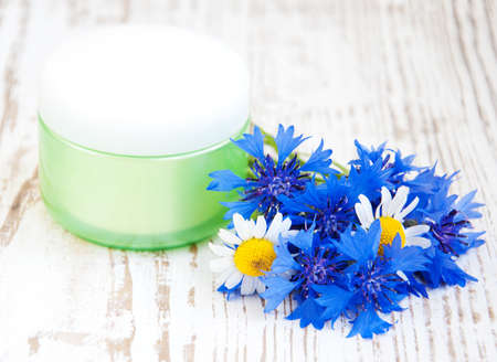 container with cream  and cornflowers on white wooden backgroundの写真素材