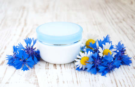 container with cream  and cornflowers on white wooden backgroundの写真素材