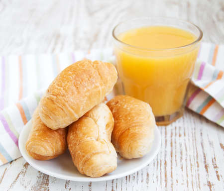 Fresh-baked croissant and   orange juice on a wooden backgroundの写真素材