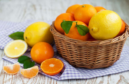 A basket of fresh tangerines and lemons on a wooden backgroundの写真素材