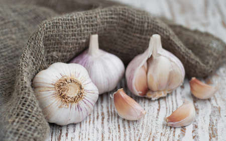 Burlap sack with garlic on a wooden background