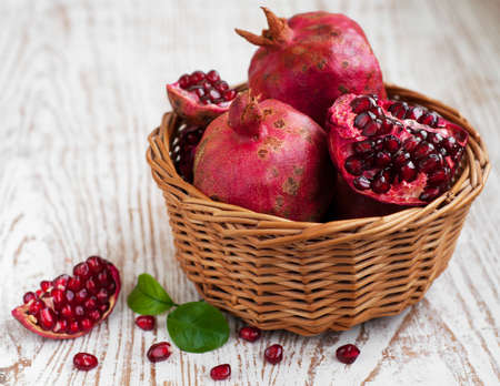 Basket with pomegranate on  old white wooden backgroundの写真素材