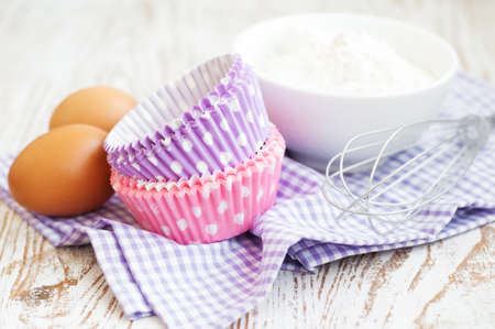 Cupcake cases and ingredients for muffins on a wooden 